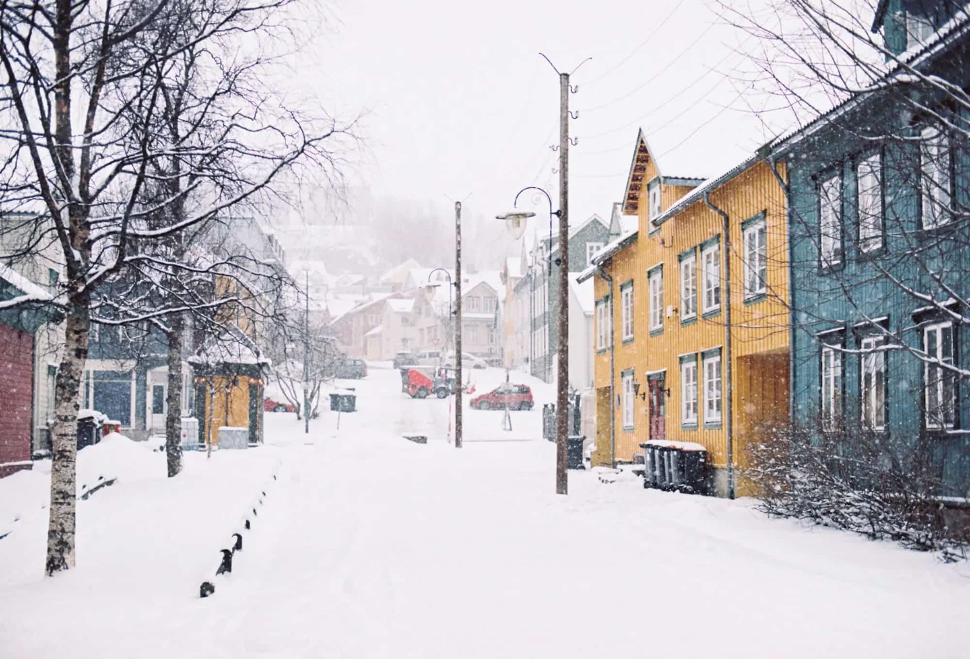 A residential street of wooden houses under heavy snowfall